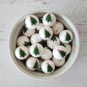 May include: A bowl filled with white round beads with a green Christmas tree design and a red star on top.