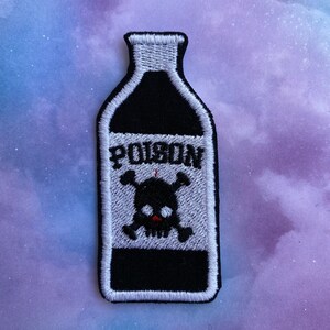 May include: Black and white embroidered patch of a poison bottle with a skull and crossbones. The bottle is outlined in white and the text "POISON" is printed on the label.