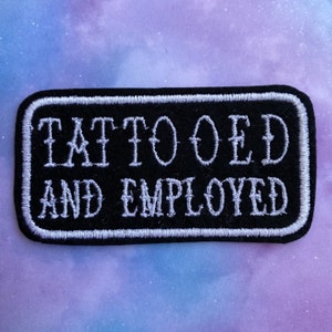 May include: Black embroidered patch with white stitching. The patch reads "Tattooed and Employed".