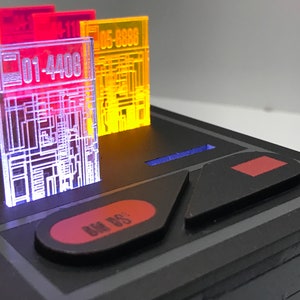 May include: A black electronic device with a red button labeled "Data Bus" and a red button with a square shape. There are four translucent plastic cards with numbers and circuit board designs in green, red, yellow, and blue.