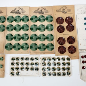 Puede incluir: Surtido de botones vintage en tarjetas. Los botones son de varios colores, incluyendo verde, marrón, azul y rojo. Algunos botones tienen un acabado metálico. Las tarjetas tienen texto en francés, incluyendo "Bruxelles Mode".