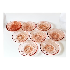 Può includere: Set di otto piatti da dessert in vetro rosa con un motivo a diamante e un design a spirale al centro.