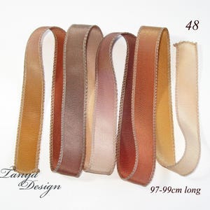 May include: Five different colored satin ribbon spools, each with a different shade of brown, beige, and orange. The ribbons are 97-99cm long.