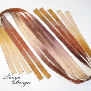 May include: Assortment of ten thin, hand-dyed silk ribbons in shades of brown, beige, and cream. The ribbons are arranged in a fan shape and have a subtle ombre effect.