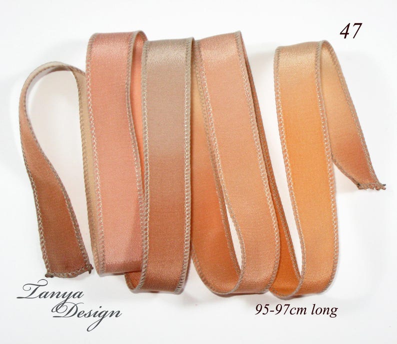 May include: Four strands of peach and beige ombre satin ribbon, each approximately 95-97 cm long. The ribbon has a subtle sheen and a delicate, stitched edge.
