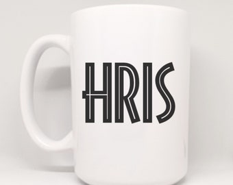 May include: White ceramic mug with a black outline of the name "CHRIS" printed on the front.