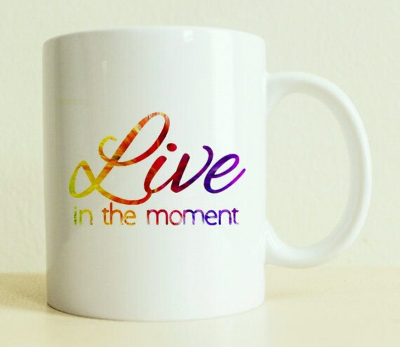 May include: White ceramic mug with a colorful, rainbow-like design that says "Live in the moment".