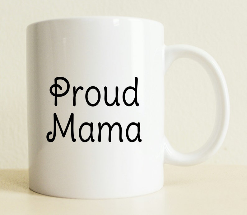 May include: White ceramic coffee mug with black text that reads "Proud Mama".