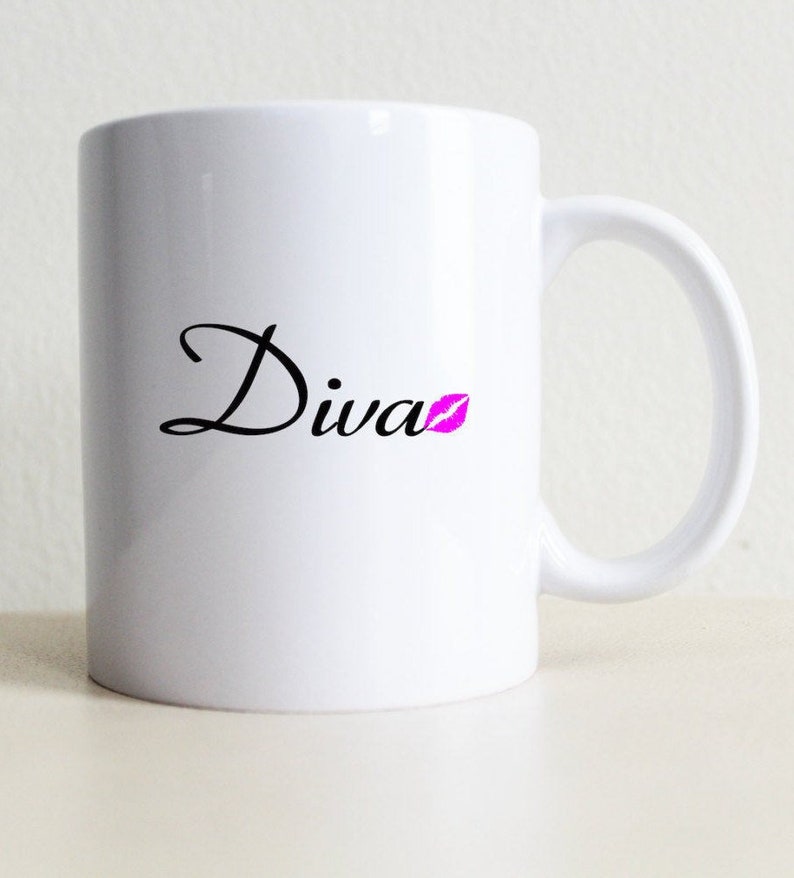 May include: White ceramic mug with a black cursive word "Diva" and a pink lip print.