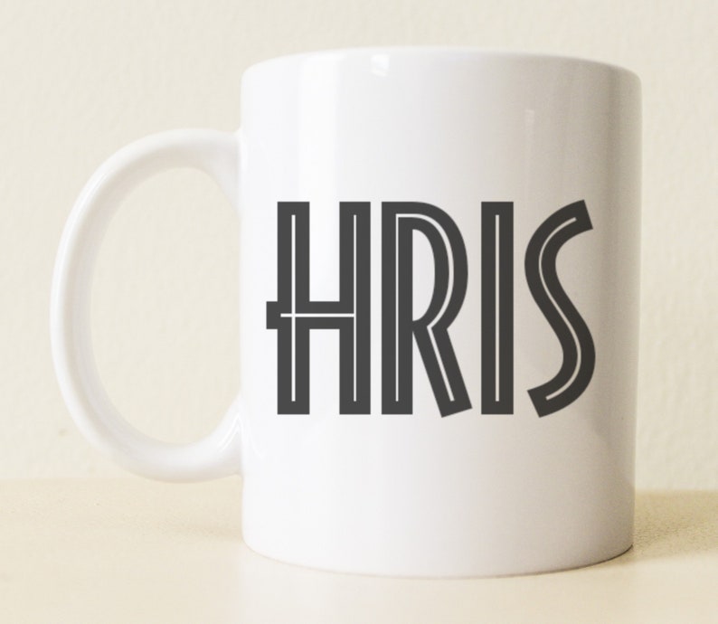 May include: White ceramic mug with a black outline of the word "CHRIS" printed on the front.