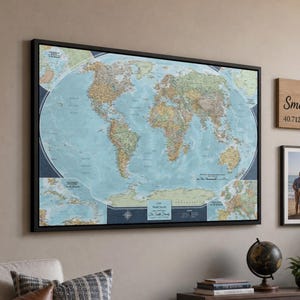 May include: A large framed world map with blue oceans and tan continents, flanked by two square framed landscape photos, a vertical family photo, and a rectangular wooden sign reading The Smith Family with coordinates 40.7128 N, 74.0060 W.