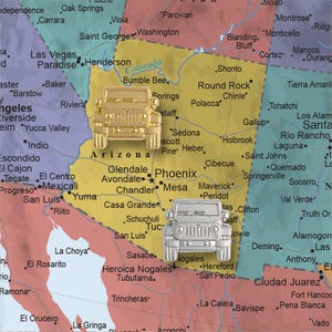May include: A map of the United States with two Jeep Wrangler models placed on the state of Arizona. The Jeep on the left is gold and the Jeep on the right is silver.