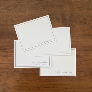 May include: Four white note cards with different family names printed on them. The names are "The Jennings Family", "The Killeen Family", "BrendaStier", and "The Reynolds Family".