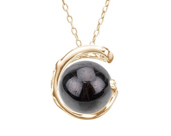 May include: A gold necklace with a black gemstone pendant. The pendant is a sphere held within a gold, open-circle design.