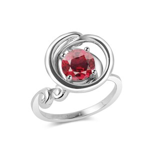 Puede incluir: Un anillo de plata con una piedra preciosa roja engastada en un diseño abierto y en espiral.