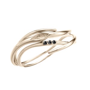 Può includere: Un anello in oro con un design delicato e organico, che presenta una forma a foglia e tre diamanti neri.