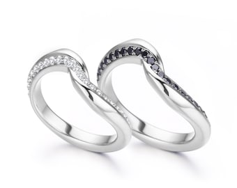 Könnte beinhalten: Zwei silberne Ringe mit einem geschwungenen Design. Ein Ring ist mit weißen Diamanten besetzt, der andere mit schwarzen Diamanten.
