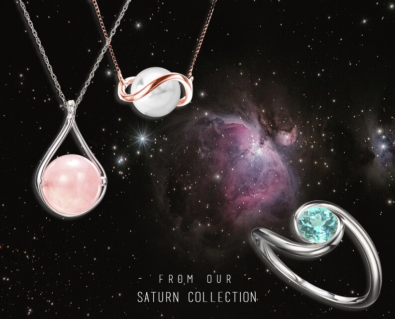 May include: Three silver necklaces with different pendants. The first necklace has a pink stone in a teardrop-shaped setting. The second necklace has a white pearl in a silver and rose gold setting. The third necklace has a light blue stone in a silver setting. The necklaces are displayed against a black background with a nebula.