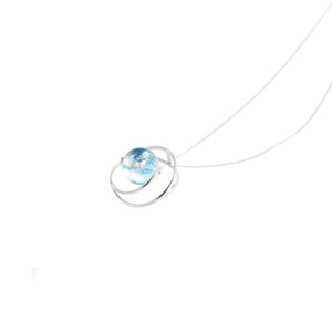 May include: A silver necklace with a blue glass orb pendant. The orb is surrounded by a silver ring.