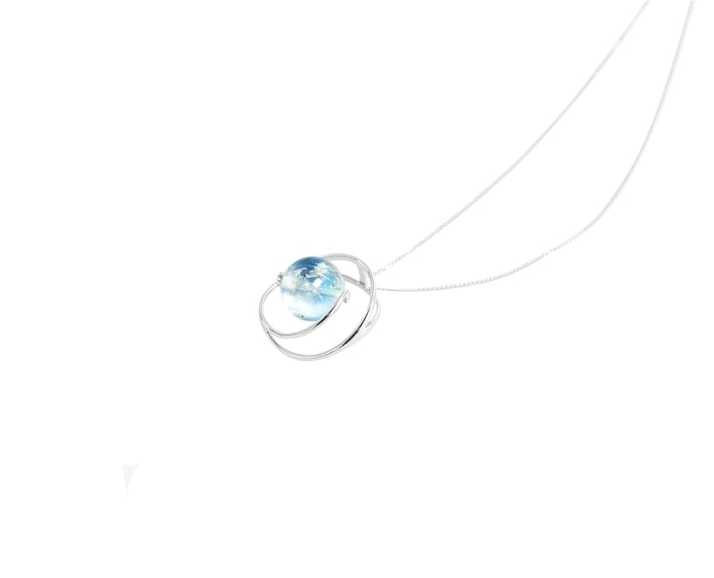 May include: A silver necklace with a blue glass orb pendant. The orb is surrounded by a silver ring.