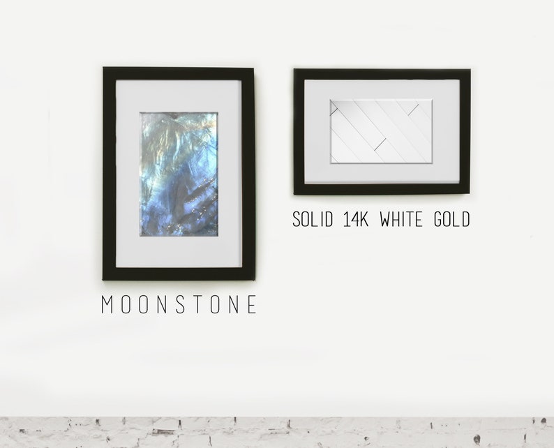 May include: Two framed images on a white wall. The image on the left is a close-up of a blue and green iridescent gemstone with the text "MOONSTONE" below. The image on the right is a white geometric pattern with the text "SOLID 14K WHITE GOLD" below.