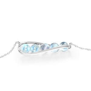 May include: A silver necklace with a curved pendant that holds four iridescent blue moonstone beads.