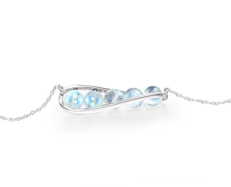 May include: A silver necklace with a curved pendant that holds four iridescent blue moonstone beads.