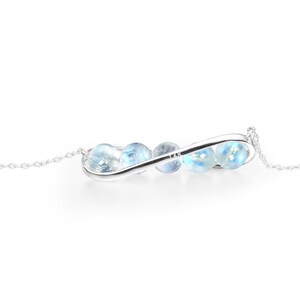 May include: A silver infinity necklace with a chain and blue gemstone beads.