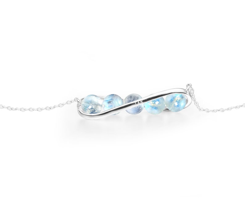 May include: A silver infinity necklace with a chain and blue gemstone beads.