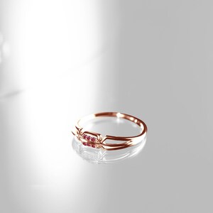 May include: A delicate gold ring with three small ruby stones set in a simple band.