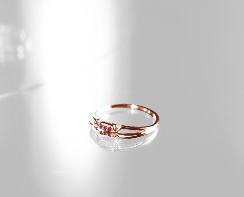 May include: A delicate gold ring with three small ruby stones set in a simple band.