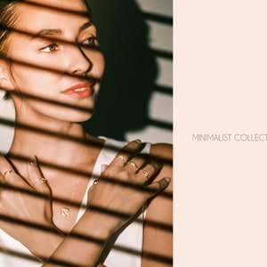 May include: A woman wearing a white shirt and gold rings. The image is in a minimalist style with the text "MINIMALIST COLLECTION" in the background.
