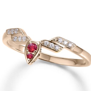 May include: A gold ring with a unique, curved design. The ring is set with two red gemstones and several smaller white gemstones.