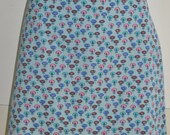 Jupe-short : fond bleu clair & motif petites fleurs rose, turquoise, marron. Poche latérale et arrière. Bordure de ceinture distinctive. Fermeture éclair au dos