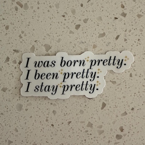 May include: A white sticker with the text "I was born pretty: I been pretty: I stay pretty." in black script. The sticker has a decorative border with small gold starbursts.