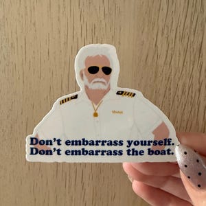 May include: A white sticker featuring a cartoon illustration of a man in a captain's uniform wearing sunglasses. The sticker has the text "Don't embarrass yourself. Don't embarrass the boat."