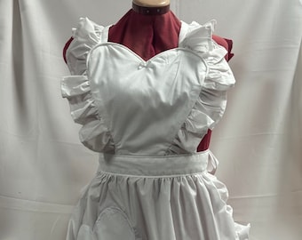 May include: White heart-shaped apron with ruffled trim and a heart-shaped pocket. The apron is made of a lightweight fabric and has adjustable straps.