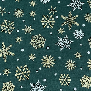 May include: A green fabric with a repeating pattern of gold and white snowflakes. The snowflakes are of various sizes and designs.