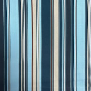 Può includere: Un tessuto a righe con righe blu, marroni e beige alternate. Il tessuto ha un motivo a righe verticali.
