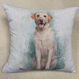 Pode incluir: Uma almofada bege com uma imagem em estilo aquarela de um labrador retriever marrom claro sentado com a língua para fora. O fundo é uma aquarela azul claro e verde.