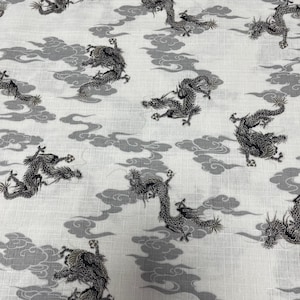 Könnte beinhalten: Weißer Stoff mit einem sich wiederholenden Muster aus schwarzen Drachen und grauen Wolken. Die Drachen sind stilisiert und haben ein traditionelles japanisches Design.