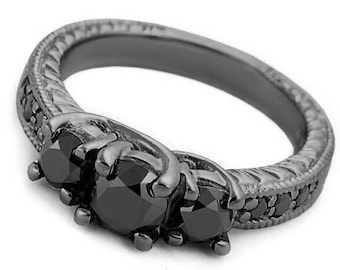 May include: Black engagement ring with three black diamonds set in a black metal band. The band is decorated with a textured design.