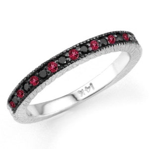 May include: A silver band ring with a row of black diamonds and red gemstones. The ring has a textured band and is marked "14K".