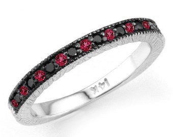 May include: A silver band ring with a row of black diamonds and red gemstones. The ring has a textured band and is marked "14K".