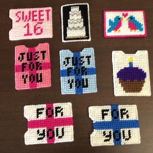 May include: A collection of handmade plastic canvas card holders in various colors. Designs include a birthday cake, a cupcake, two birds, and the phrases "Sweet 16" and "Just For You". The card holders are in pink, blue, and white.