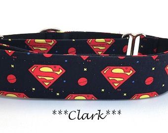 May include: A black dog collar featuring the Superman logo in red and yellow. The collar has a repeating pattern of the logo, red circles, blue dots, and yellow stars. The text "***Clark***" is at the bottom.