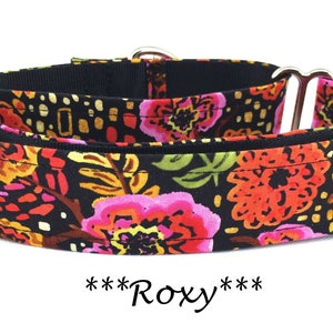 May include: A black dog collar with a floral pattern in shades of pink, orange, and yellow. The collar has silver hardware and the text "***Roxy***" is printed below the collar.