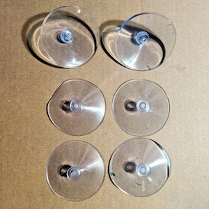 May include: Six clear plastic suction cups with a small knob in the center of each. The suction cups are arranged in two rows of three.