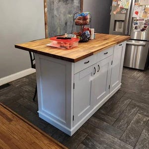kitchen island white with 2 drawers and 2 storage cabinets with trash compartment. Custom kitchen island with overhang for seating.