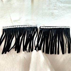 May include: Two black fringe trims with a row of clear rhinestones at the top.